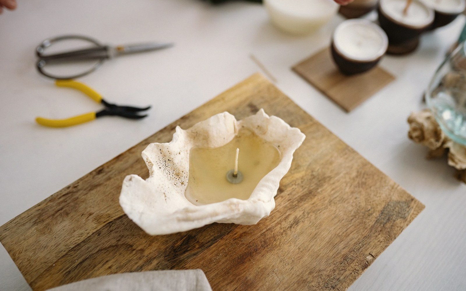 A short length of trimmed wick resting on a pale wax surface beside its candle, close-up with shallow depth of field
